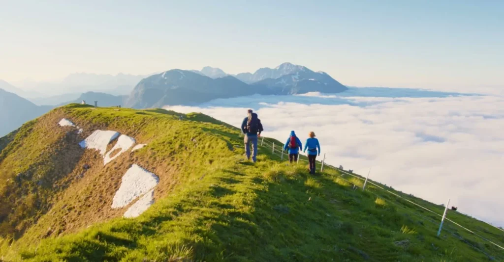 Three hikers above cloud line, sunrise