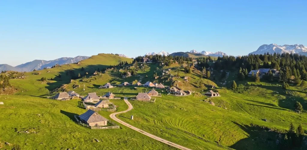 Velika Planina aerial, golden light, huts scattered on plateau